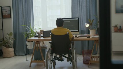 Back view of coder in wheelchair developing app on computer