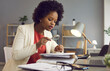 © Studio Romantic - Concentrated african american businesswoman reads and studies documents with a magnifying glass. Female office worker, accountant or secretary doing his job sitting in the office.