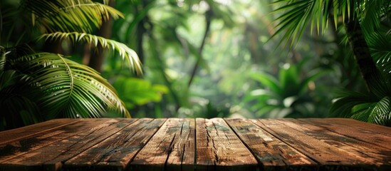 Empty wooden tabletop with a blurred background of a green tropical jungle in summer The table provides copyspace for displaying advertising products alongside a stunning forest banner background