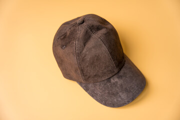 Womens dark brown baseball cap made of genuine suede on a peach fuzz background.