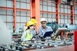 © sirichai - factory workers in uniform together work inspecting operation manufacturing Metal Roofing Sheet Machine in the factory metal sheet, Metalwork roof manufacturing and quality control process.