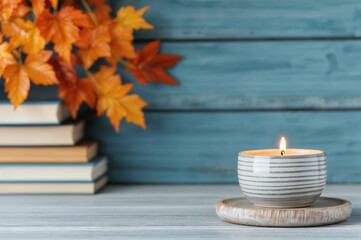 Poster - Burning candle on empty table with autumn leaves decoration