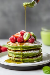 Wall Mural - Decadent matcha pancakes stacked high, topped with fresh berries and drizzled with syrup, creating a vibrant and delectable breakfast treat.