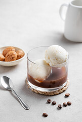 Wall Mural - Affogato coffee with vanilla ice cream scoops and  espresso in a glass on a light  background with coffee beans, jug and cookies.