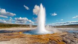 A stunning geothermal geyser erupts against a blue sky, showcasing nature's power and beauty in a serene landscape.