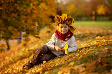 Canvas Print - Adorable little child, blond boy with crown from leaves in park on autumn day.