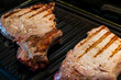 © Nestudio - Grilled Pork steaks, neck meat on grill pan. Black background. Top view.