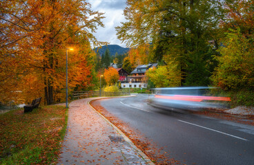 Wall Mural - blurred car on winding road with fallen leaves in autumn
