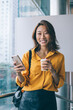 © BullRun - Half length portrait of cheerful hipster girl with smartphone mobile gadget in hand looking at camera and rejoicing during free time, prosperous woman in joyful mood using cellphone for networking