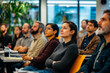 © GustavsMD - A diverse group of professionals attentively listens during a seminar in a modern office environment with natural light and plants