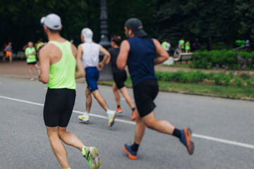 Wall Mural - Marathon runners crowd, sportsmen participants start running the half-marathon in the city streets, crowd of sportswomen joggers in motion, group athletes outdoor training competition in a summer day