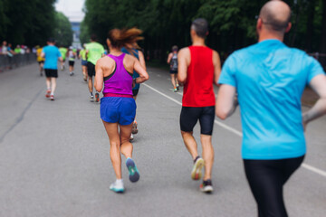 Wall Mural - Marathon runners crowd, sportsmen participants start running the half-marathon in the city streets, crowd of sportswomen joggers in motion, group athletes outdoor training competition in a summer day