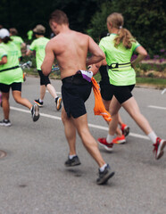 Wall Mural - Marathon runners crowd, sportsmen participants start running the half-marathon in the city streets, crowd of sportswomen joggers in motion, group athletes outdoor training competition in a summer day