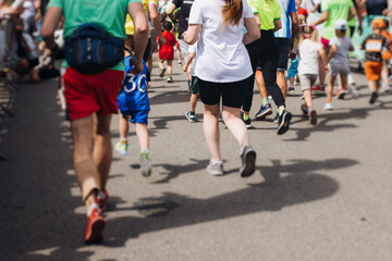 Wall Mural - Marathon runners crowd, sportsmen participants start running the half-marathon in the city streets, crowd of sportswomen joggers in motion, group athletes outdoor training competition in a summer day