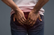 © Prostock-studio - Afro man with hemorrhoids holding his butt in pain, white background, cropped