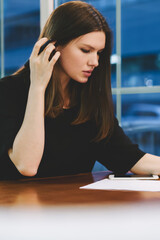 Wall Mural - Young serious hipster girl searching information about statistics of travel blogs connected to 4g internet on modern touch pad for writing plan on paper, concept of technology and communication