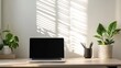 © putri syakilla - A minimalist workspace featuring a laptop, plants, and light shadows on the wall.