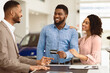 © Prostock-studio - Afro Couple Buying Car Giving Seller Credit Card Standing In Auto Dealership Office. Selective Focus
