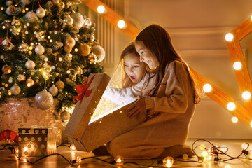 happy sibling girls opening christmas presents. children with gift boxes and christmas star. decorat
