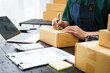 © NanSan - A man is working at his desk, preparing parcel boxes for shipment. He checks and packs items carefully, using shockproof materials, and attaches labels before sending them to customers via EMS.