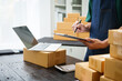 © NanSan - A man is working at his desk, preparing parcel boxes for shipment. He checks and packs items carefully, using shockproof materials, and attaches labels before sending them to customers via EMS.