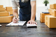 © NanSan - A man is working at his desk, preparing parcel boxes for shipment. He checks and packs items carefully, using shockproof materials, and attaches labels before sending them to customers via EMS.