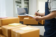 © NanSan - A man is working at his desk, preparing parcel boxes for shipment. He checks and packs items carefully, using shockproof materials, and attaches labels before sending them to customers via EMS.