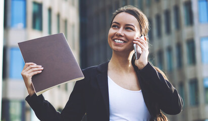 Cheerful female professional in finance world feeling excited from well done deal with colleagues calling to best friend for discussing good experience using 4g internet in roaming on cellphone