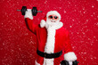 © deagreez - Active life for pensioners. Photo of retired old man white beard lift heavy dumbbells smiling strong grandpa concept wear santa costume sunglass headwear isolated red color background
