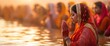 © Vasiliy - Devout woman performing Chhath puja rituals in sacred waters at sunrise with crowd of worshippers in background