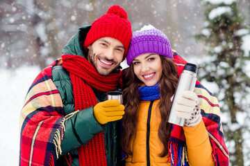 Wall Mural - Photo of cute charming marriage couple wear windbreakers drinking hot coffee covering blanket walking snowy weather outside park