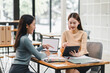 © PRIME STOCK LAB - Two women engaged in collaborative discussion at modern workspace, sharing ideas while using tablet and laptop. Their interaction reflects teamwork and creativity.