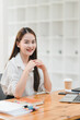 © PRIME STOCK LAB - young woman with long hair smiles confidently at desk filled with books and laptop, creating warm and inviting atmosphere in modern workspace.
