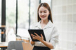 © PRIME STOCK LAB - young woman is smiling while using tablet in modern office setting, showcasing positive and productive atmosphere. Her professional attire and bright environment enhance feeling of engagement and