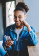 © BullRun - Portrait of excited smiling hipster girl dressed in stylish apparel looking at camera while listening favourite song from motivation playlist on cellular phone, happy woman enjoying audio book