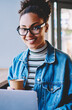 © BullRun - Portrait of happy black female student sitting in university cafeteria with takeaway cup and enjoying coffee break from e learning and research of data on laptop computer, concept of autodidact