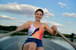 © Connect Images - Smiling woman rowing a boat on a serene lake with blue skies in the background.