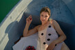© Connect Images - Woman relaxing in a boat wearing a polka-dot dress with cherries by her side in the sunlight.