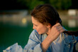 © Connect Images - Close-up of a smiling young woman tying her hair by a calm lake at dusk.
