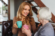 © InsideCreativeHouse - Mature woman and adult daughter resting on sofa enjoying coffee or tea