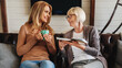 © InsideCreativeHouse - Mature women reading book with her daughter drinking coffee at home