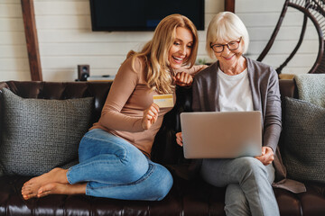 Senior woman and daughter using laptop and credit card for shopping online, having rest at home