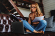 © InsideCreativeHouse - Middle aged woman working at home sitting on sofa in the living room with laptop and checking documents