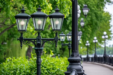 Classic black street lamps line park pathway surrounded by vibrant green trees, overcast lighting gives soft, peaceful atmosphere as lamps provide traditional and inviting charm.