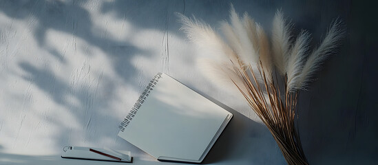 Poster - Pampas grass beside notebook on a grey background with copy space image