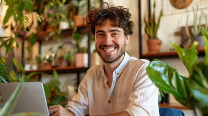 Poster - A man is sitting at a table with a laptop and smiling