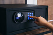 © NewSaetiew - Close-up of a person hand entering a password to unlock and open the safe box door.
