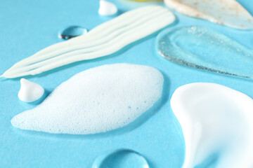 Wall Mural - Smears of different cosmetic products on light blue background, closeup