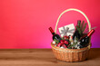 © New Africa - Wicker gift basket with wine on wooden table against pink background, space for text