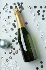 Poster - Flat lay composition with bottle of sparkling wine, shiny confetti and other Christmas decor on light grey background